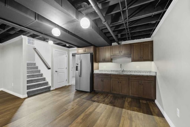 kitchen featuring light stone countertops, dark hardwood / wood-style flooring, stainless steel refrigerator with ice dispenser, and sink