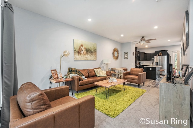 living room with ceiling fan, sink, and light colored carpet