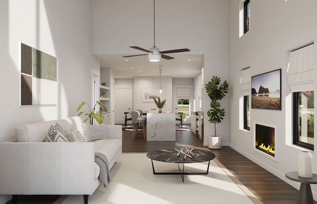 living room featuring ceiling fan, wood-type flooring, and a towering ceiling