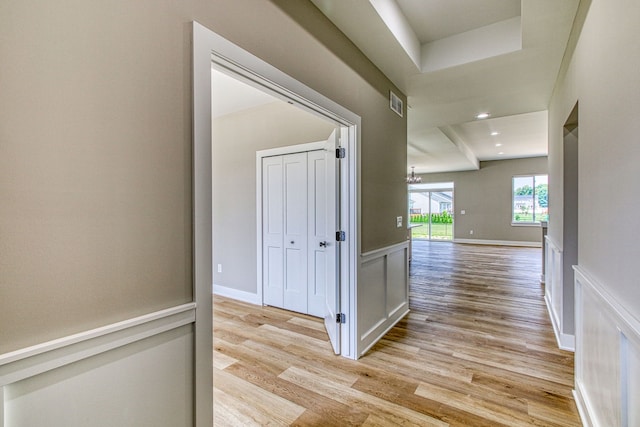 corridor with light hardwood / wood-style floors and an inviting chandelier