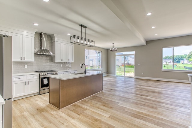 kitchen with wall chimney exhaust hood, plenty of natural light, white cabinetry, and stainless steel appliances