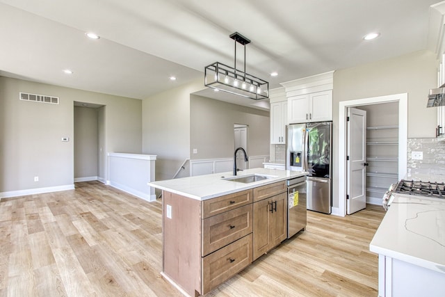 kitchen with light stone countertops, white cabinetry, sink, and a kitchen island with sink