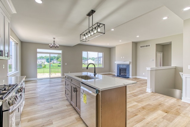 kitchen with sink, stainless steel appliances, a center island with sink, and light wood-type flooring