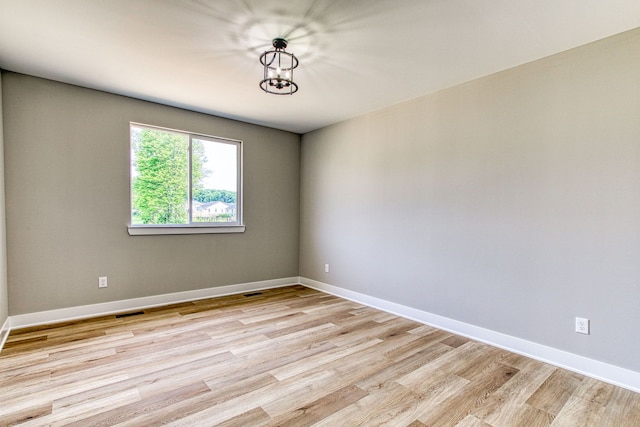 unfurnished room featuring light wood-type flooring and a chandelier