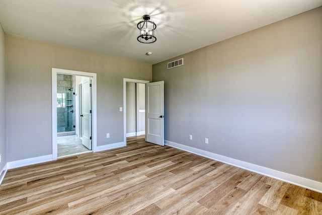 unfurnished bedroom featuring connected bathroom and light hardwood / wood-style flooring