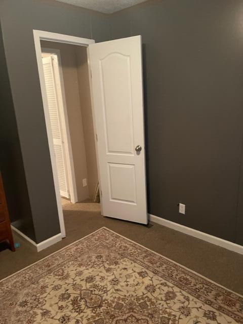 unfurnished bedroom with a closet and dark colored carpet