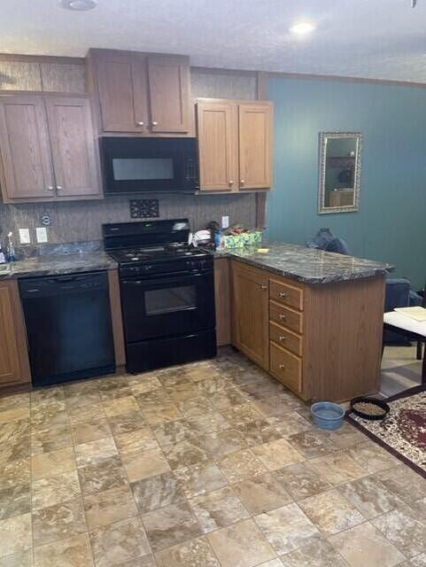 kitchen with kitchen peninsula, decorative backsplash, dark stone countertops, and black appliances