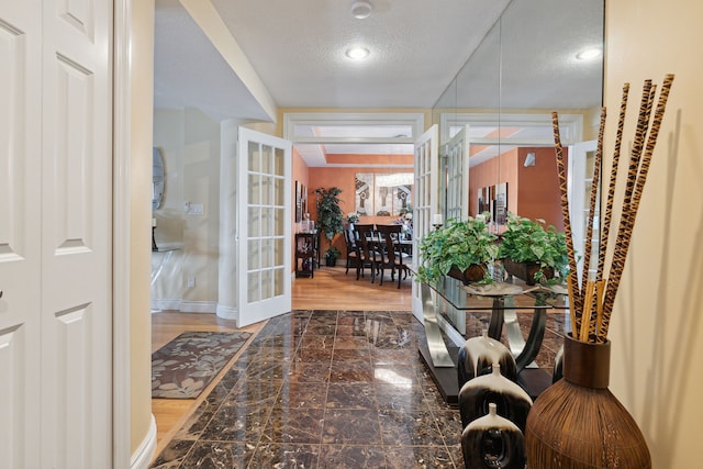 interior space with a textured ceiling and french doors