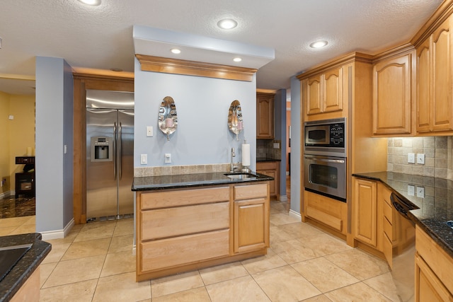 kitchen with tasteful backsplash, built in appliances, sink, and light tile patterned flooring