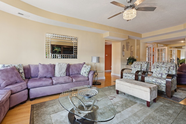 living room with hardwood / wood-style flooring, ceiling fan, and a textured ceiling