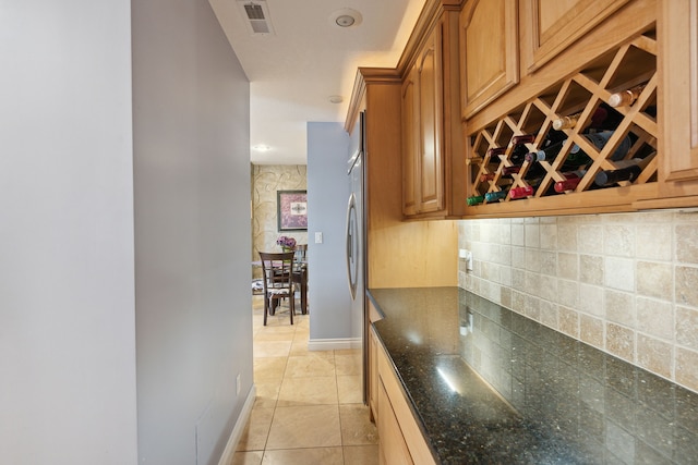 kitchen with light tile patterned flooring, dark stone countertops, and tasteful backsplash