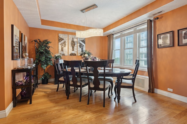 dining space featuring light wood-type flooring and a textured ceiling