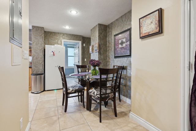 tiled dining area featuring electric panel and a textured ceiling