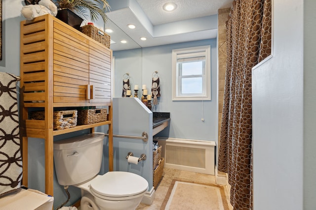 bathroom with a textured ceiling, toilet, and curtained shower