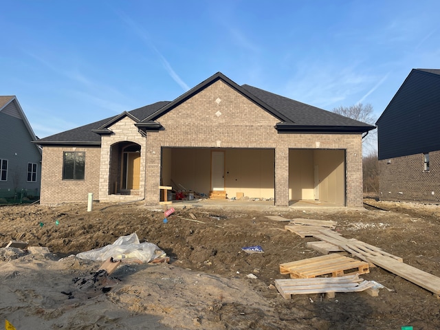 property in mid-construction with brick siding, a shingled roof, and a garage