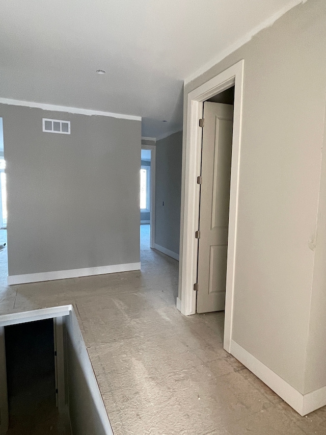 hallway featuring visible vents, baseboards, and crown molding