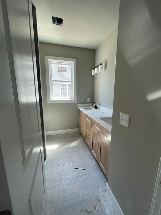 bathroom with baseboards, a sink, and double vanity