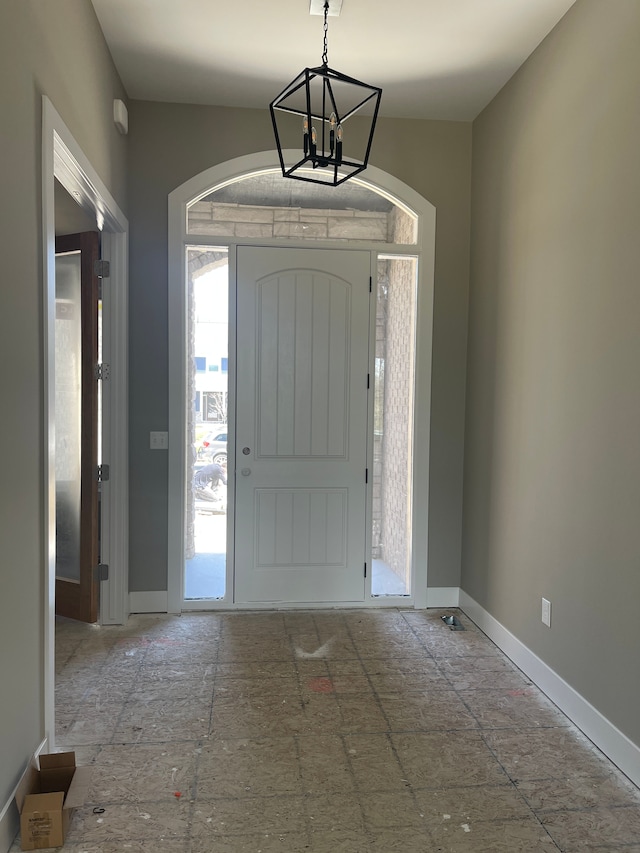 entrance foyer with arched walkways, baseboards, a notable chandelier, and a wealth of natural light