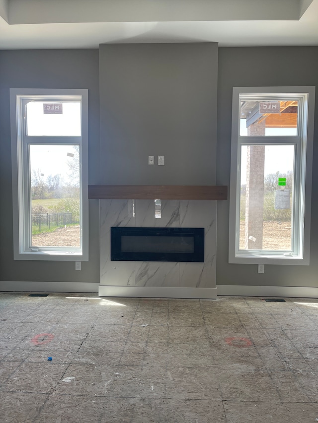 unfurnished living room featuring a wealth of natural light and a premium fireplace