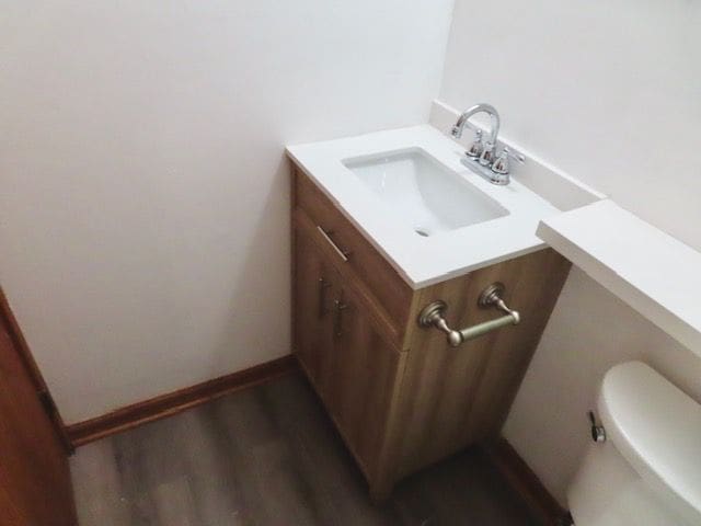 bathroom featuring toilet, vanity, and hardwood / wood-style flooring