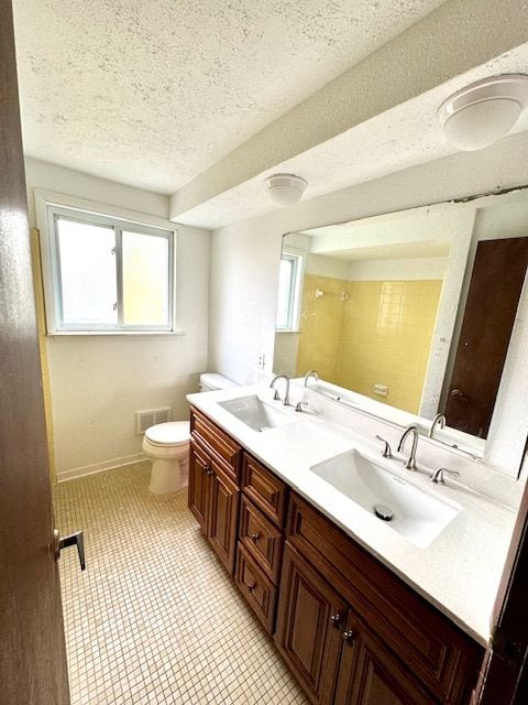 bathroom featuring tile patterned flooring, vanity, a textured ceiling, and toilet