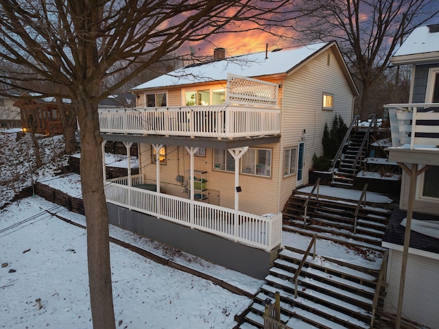 snow covered back of property featuring a balcony