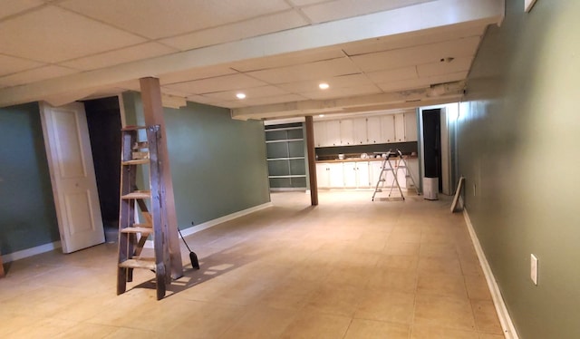 basement featuring a paneled ceiling and light tile patterned floors