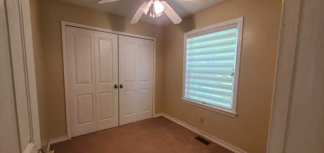 unfurnished bedroom featuring carpet flooring, ceiling fan, multiple windows, and a closet