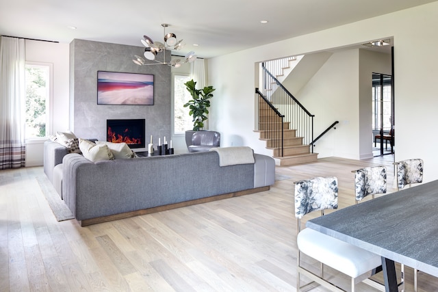 living room featuring an inviting chandelier, a fireplace, and light hardwood / wood-style flooring