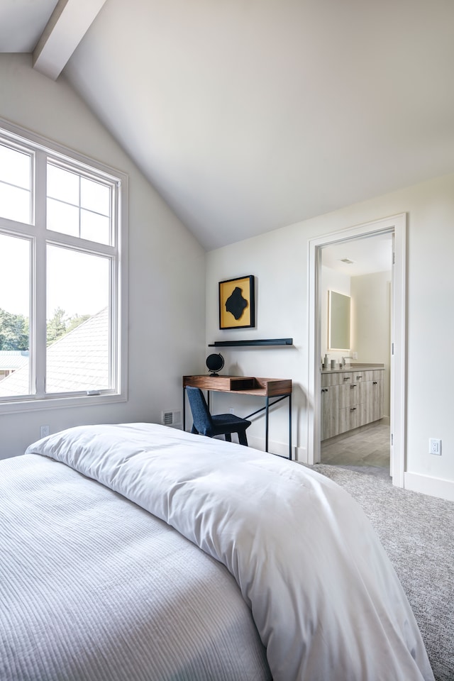 bedroom with vaulted ceiling with beams, ensuite bathroom, and light carpet