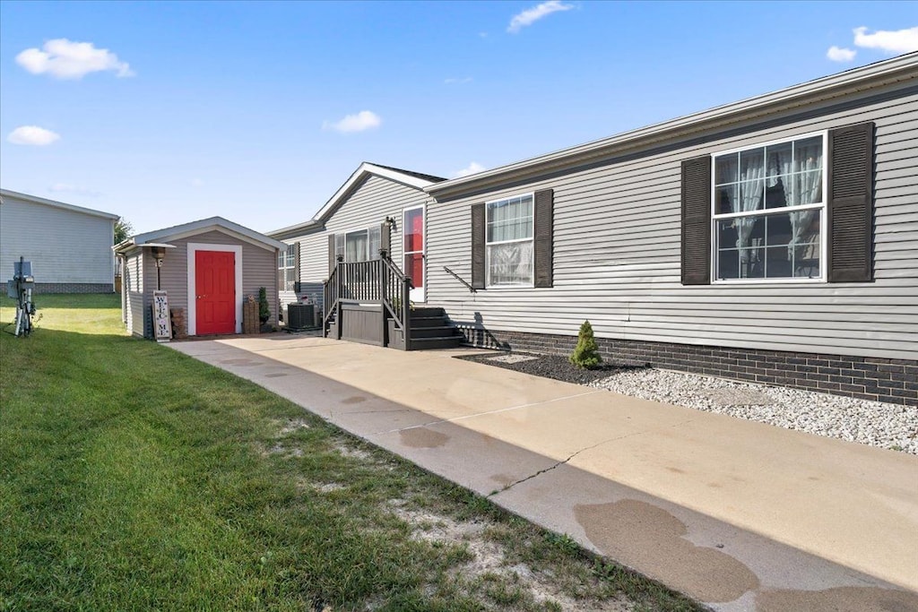 manufactured / mobile home with a storage unit, cooling unit, and a front yard