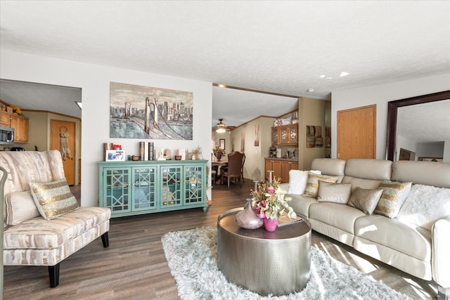 living room featuring hardwood / wood-style floors, ceiling fan, a textured ceiling, and vaulted ceiling