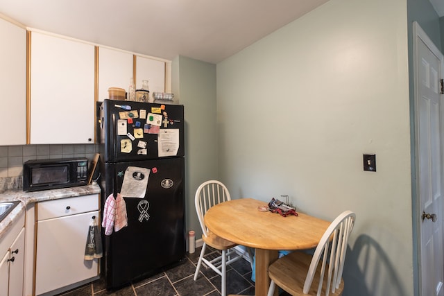 kitchen with black appliances, white cabinetry, backsplash, and dark tile patterned flooring