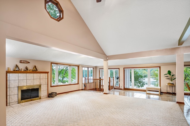 unfurnished living room featuring tile patterned flooring, high vaulted ceiling, a tile fireplace, and a wealth of natural light