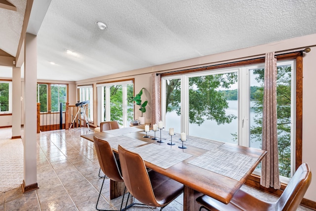 tiled dining space with a textured ceiling and vaulted ceiling