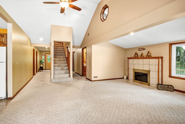 unfurnished living room with ceiling fan, light carpet, high vaulted ceiling, and a tiled fireplace