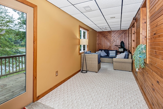 carpeted living room with a paneled ceiling and wooden walls