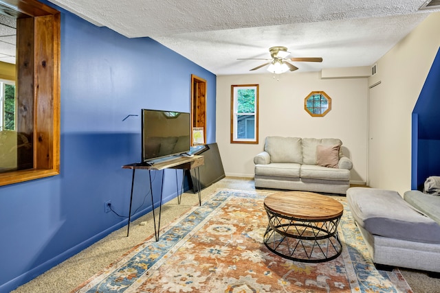 carpeted living room with ceiling fan and a textured ceiling