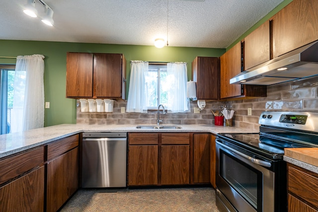 kitchen featuring appliances with stainless steel finishes, tasteful backsplash, a textured ceiling, sink, and range hood