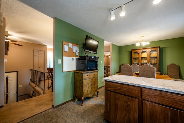 kitchen with ceiling fan with notable chandelier, dark carpet, and a textured ceiling