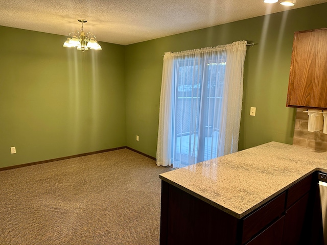 kitchen featuring dark brown cabinetry, light colored carpet, a textured ceiling, and a notable chandelier