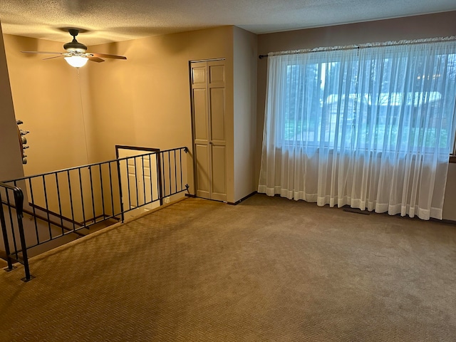 carpeted spare room with a textured ceiling and ceiling fan