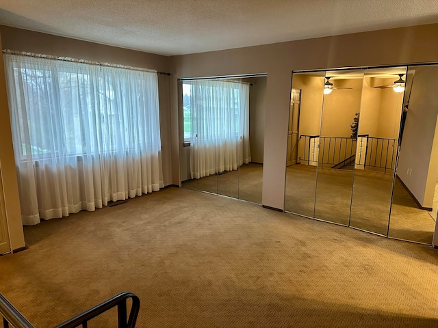 carpeted spare room with a textured ceiling and ceiling fan