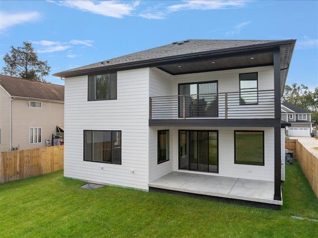 rear view of property featuring a yard, a patio, and a balcony