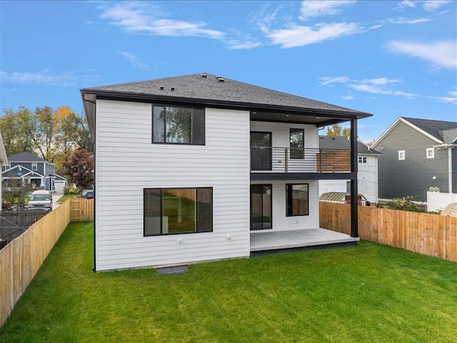 rear view of property featuring a lawn, a patio area, and a balcony