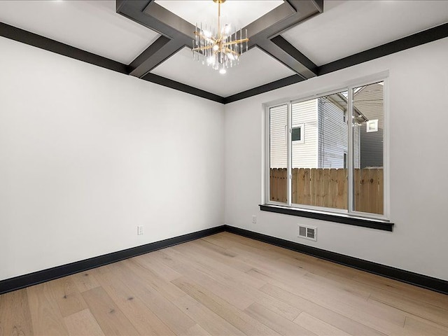 empty room featuring a chandelier, light hardwood / wood-style floors, and coffered ceiling