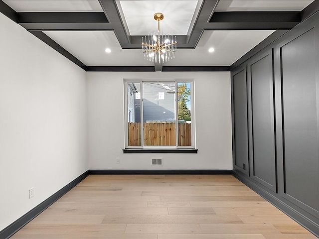 spare room featuring a chandelier, beam ceiling, and light hardwood / wood-style floors