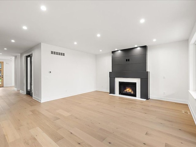 unfurnished living room with a large fireplace and light wood-type flooring