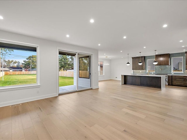 unfurnished living room featuring light wood-type flooring and sink