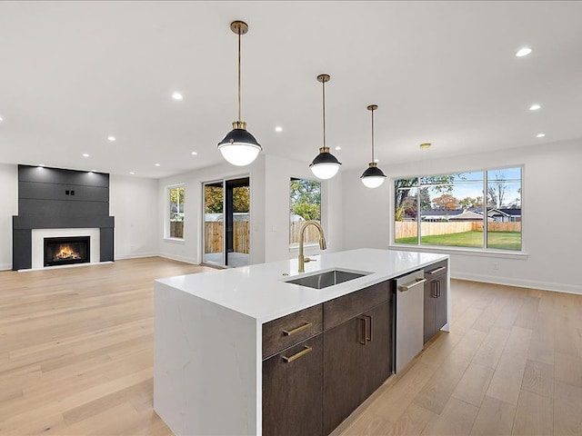 kitchen featuring sink, hanging light fixtures, a center island with sink, and light hardwood / wood-style flooring